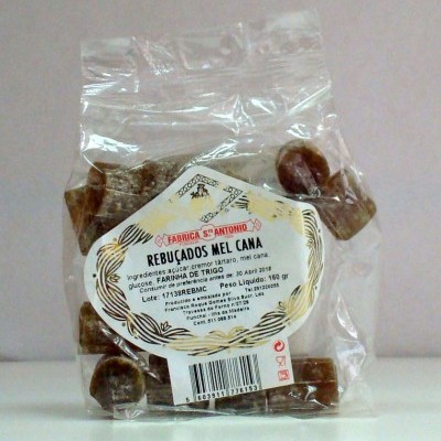 Pacote transparente com rebuçados castanhos e rótulo branco com texto