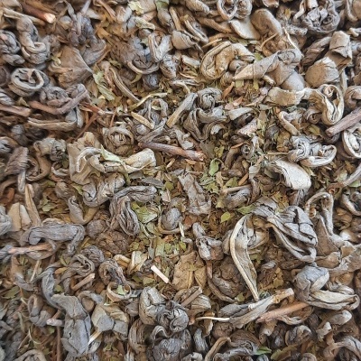 Folhas de chá secas e enroladas castanhas e verdes com textura rugosa