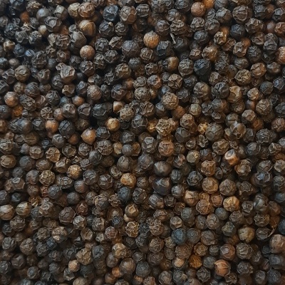 Grãos inteiros de pimenta preta com textura rugosa e cor preta e castanha.