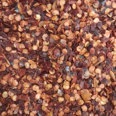 Flocos de pimenta vermelha seca com sementes visíveis numa superfície transparente