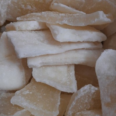 Pedaços irregulares de côco seco e açucarado, cor branca e amarelada