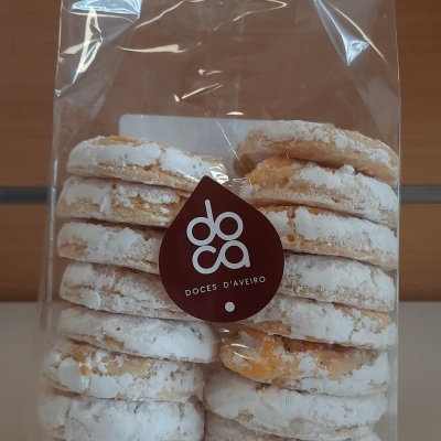 Pacote transparente com bolachas cobertas de açúcar em pó e rótulo 'doca DOCES D'AVEIRO'