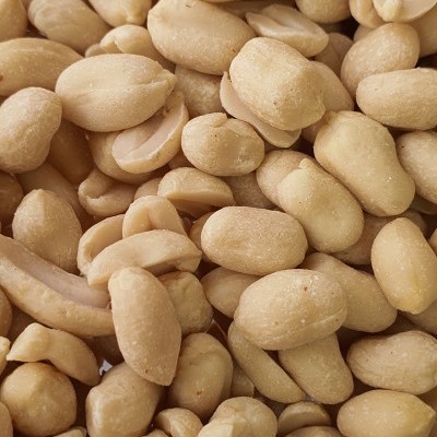 Amendoins descascados bege claro com textura lisa, texto parcial 'NUS' e 'FARINHA' visível.