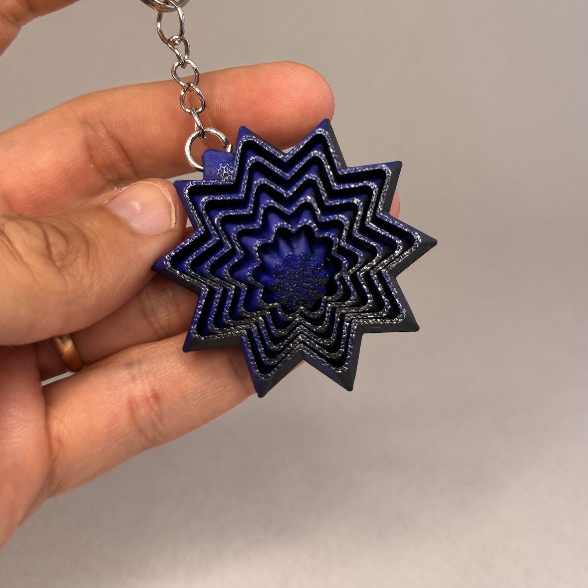 Porta-Chaves Estrela Sensorial 5 cm Chaveiro em forma de estrela azul com vários níveis sobre fundo cinzento