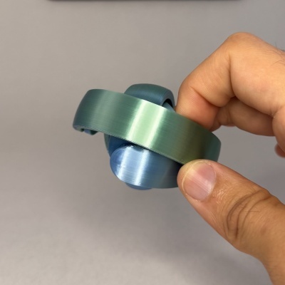 Anel azul e verde esmeralda com acabamento escovado segurado pela mão
