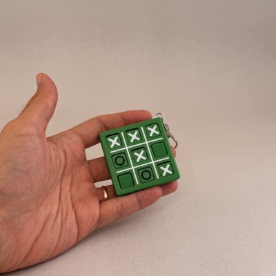 Mini jogo da velha em verde com peças móveis segurado por mão