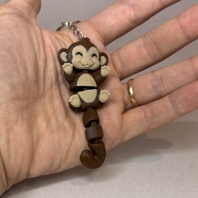 Chaveiro macaco castanho e bege na mão de uma pessoa