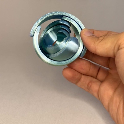 Anel metálico azul-turquesa com textura, segurado na mão