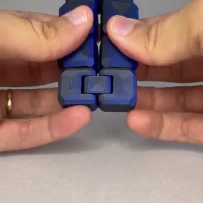 Mãos manipulando cubo fidget articulado azul e preto transformando sua forma.