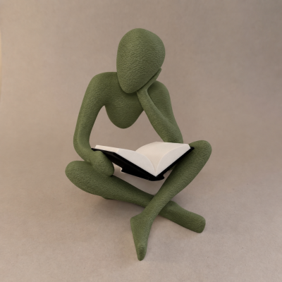 Escultura verde de figura humana a ler livro com capa preta em fundo bege