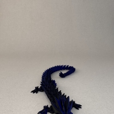 Figura decorativa de lagarto azul e preto sobre superfície cinza