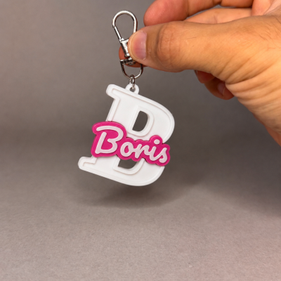 Chaveiro de plástico com letra B branca e palavra Boris em rosa e branco