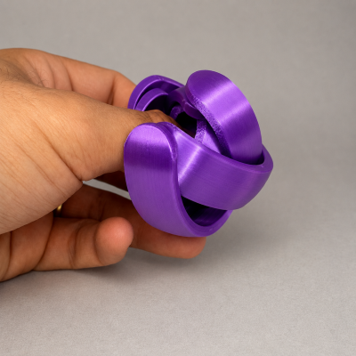 Brinquedo ou objeto entrelaçado de plástico roxo na mão sobre fundo cinzento