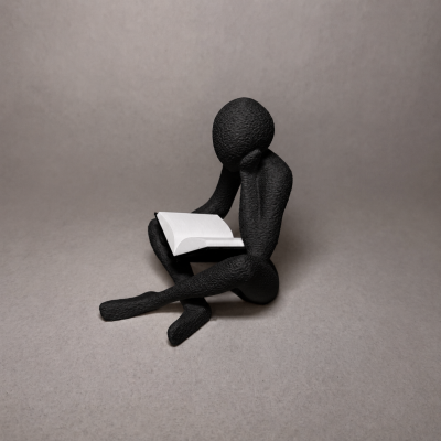 Escultura preta de figura humana sentada lendo um livro aberto