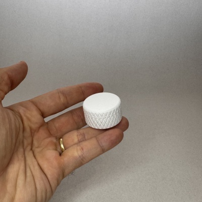 Mão segurando um objeto cilíndrico branco com textura trançada