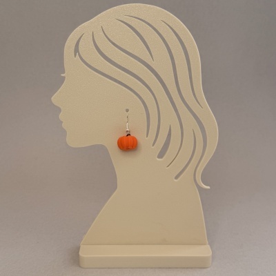 Expositor de brincos em forma de perfil feminino bege com brinco de abóbora laranja