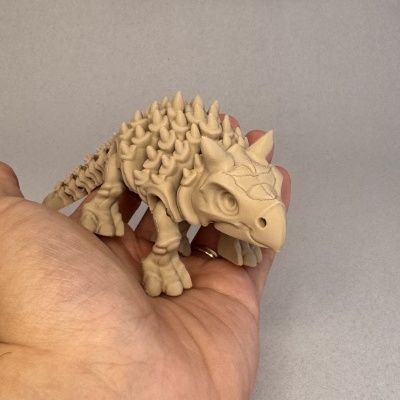 Figurinha de dinossauro Anquilossauro bege clara com texturas de espinhos numa mão
