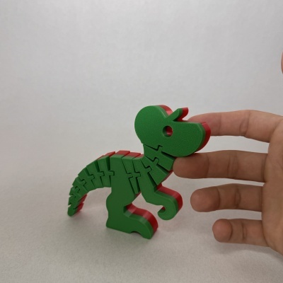 Figura de dinossauro verde e vermelho articulada e segurada por dedos