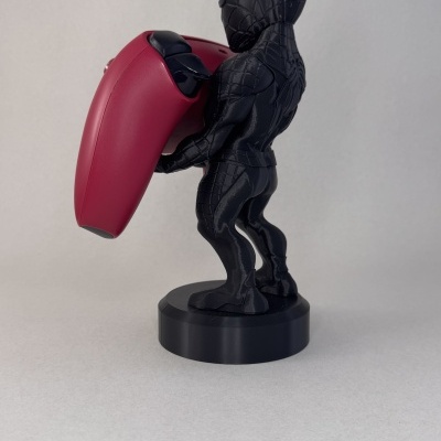 Figura de herói preta segurando dispositivo vermelho sobre base preta