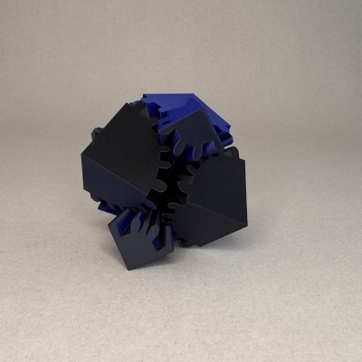 Peça 3D plástica preta e azul com formato irregular sobre superfície cinzenta
