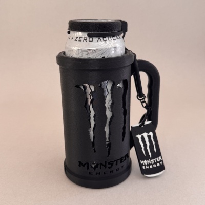 Lata de Monster Energy branca em suporte preto com o logo recortado e etiqueta pendurada, texto ZERO AÇÚCAR visível.