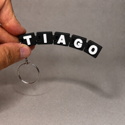 Porta-chaves com letras pretas e brancas formando TIAGO.