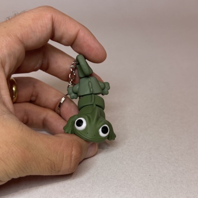 Porta-chaves em forma de crocodilo verde segurado por uma mão com fundo branco
