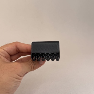 Porta-fones preto com seis fendas, sendo segurado por uma mão sobre fundo branco