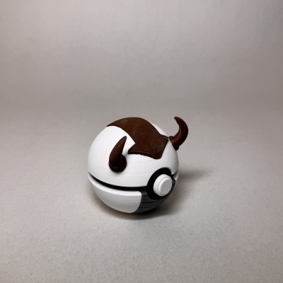 Figura redonda branca e castanha com chifres castanhos sobre superfície cinzenta