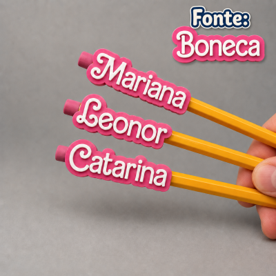 Três lápis amarelos com nomes em borrachas rosa contra fundo cinza.