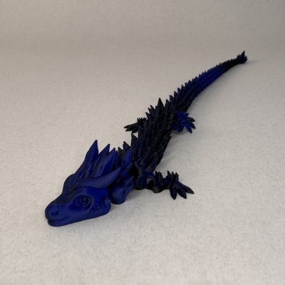 Figura de dragão preto e azul com detalhes texturizados em superfície clara