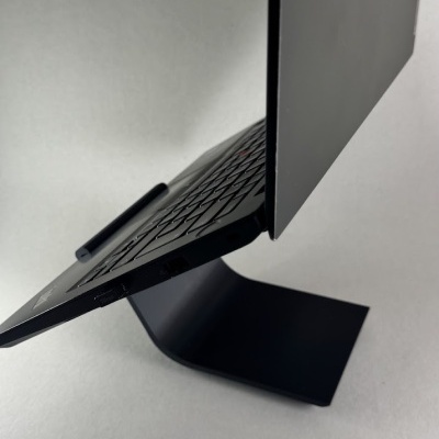 Computador portátil preto num suporte preto sobre fundo cinzento