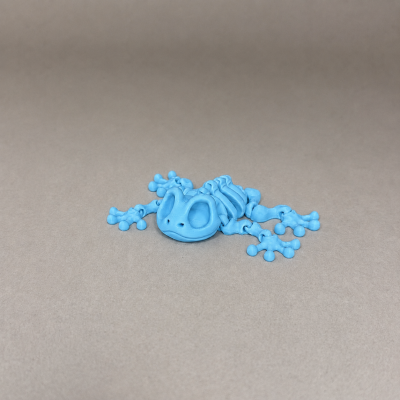 Figura de sapo esqueleto azul em plástico, sobre fundo cinzento