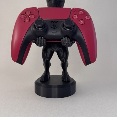 Suporte de comando Homem-Aranha negro a segurar comando PlayStation vermelho e preto.
