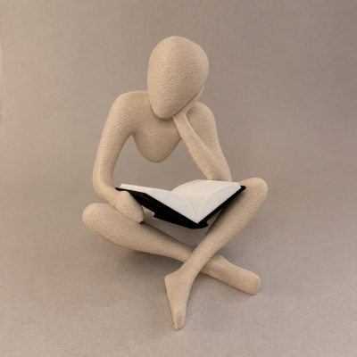 Figurino decorativo humanoide bege sentado com livro aberto