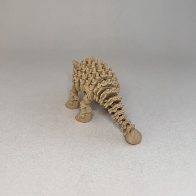Figura castanha de dinossauro Ankylosaurus com textura em relevo sobre fundo cinzento.
