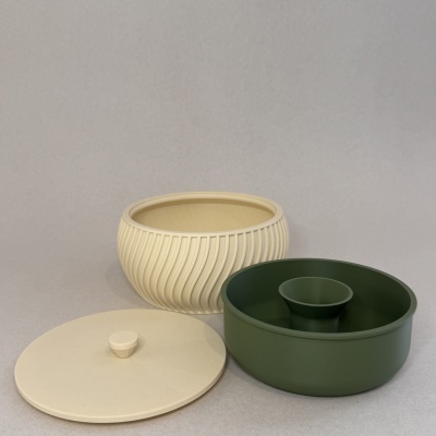 Três tigelas de plástico crem e verde escuro com tampas, uma com textura canelada.