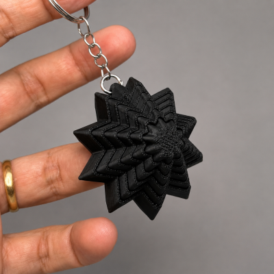 Chaveiro preto em forma de estrela em camadas com anel metálico