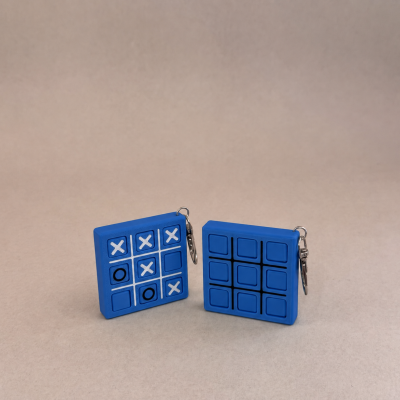 Chaveiros de silicone azul formato jogo da velha com símbolos X e O e linhas pretas.