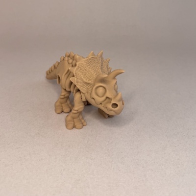 Figura de dinossauro tricératops em plástico castanho sobre fundo cinzento claro