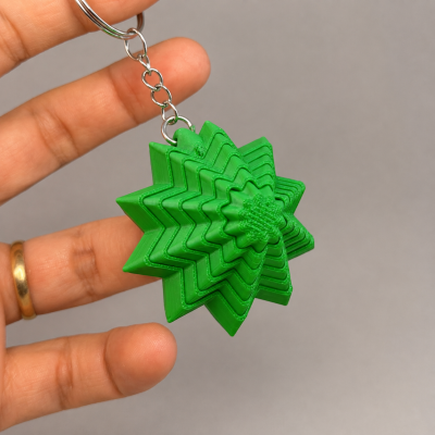 Chaveiro verde em forma de estrela tridimensional segurado por uma mão