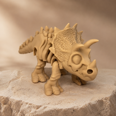 Figura de dinossauro Triceratops bege sobre superfície rochosa clara.