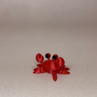 Miniatura de caranguejo vermelho em plástico sobre fundo cinza