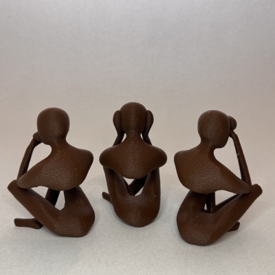 Três mini esculturas castanhas de figuras humanas em poses diversas com mãos na cabeça