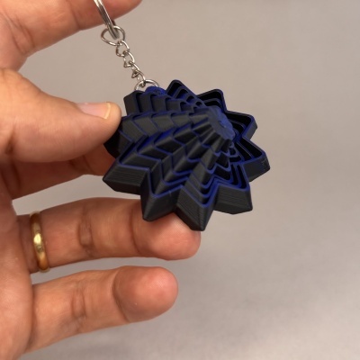 Porta-chaves estrela preto e azul em plástico com corrente metálica pendurado na mão