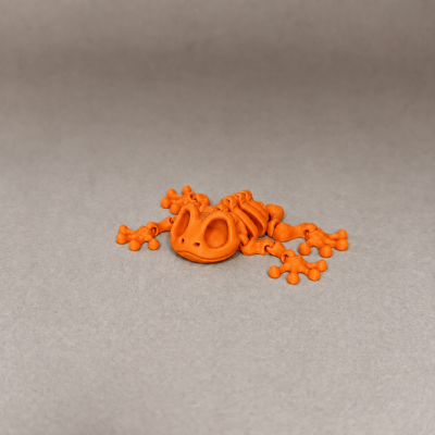 Figura de rã articulada laranja em fundo cinzento