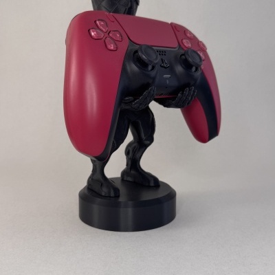 Suporte figura humana preta a segurar comando PlayStation 5 DualSense vermelho e preto