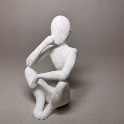 Escultura branca texturizada de figura humana sentada com mão na cabeça