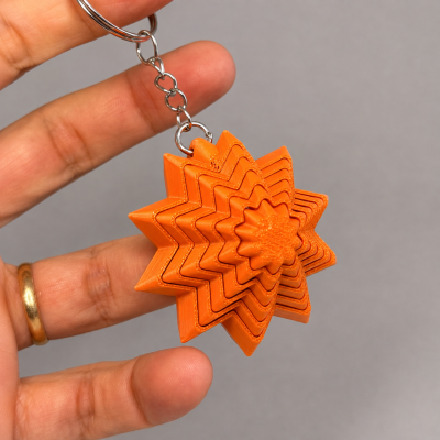 Llavero de plástico naranja con diseño de estrella en capas.