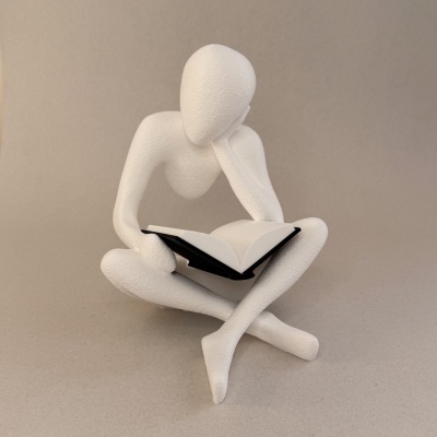 Escultura branca abstrata de figura humana lendo um livro
